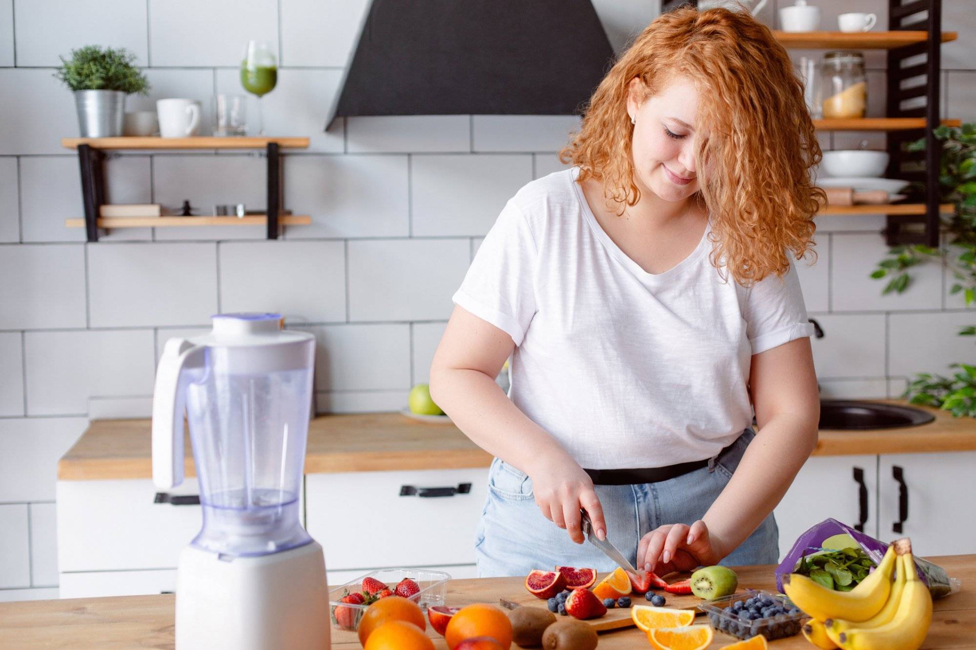 Portrait of a beautiful smiling woman preparing smoothie at home kitchen.